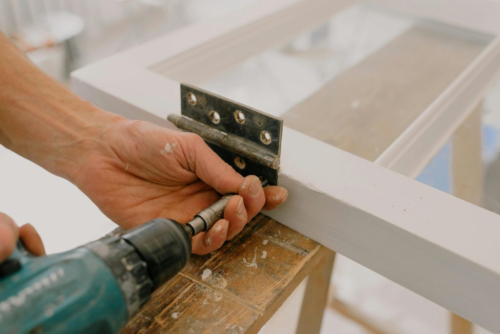 pexels-photo-5691518-5691518 Crop unrecognizable worker drilling metal hinge on white window frame during house renovation